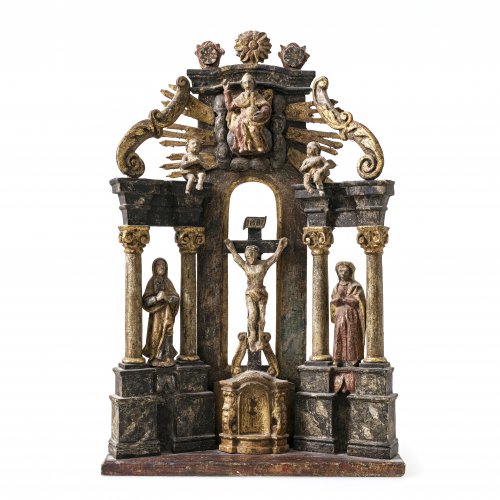 Hausaltar. Böhmen. Holz, Farb- und Goldfassung. Christus am Kreuz, Gottvater, zwischen Säulen Maria und Johannes. Alterungsspuren, leicht besch. H. 44 cm.