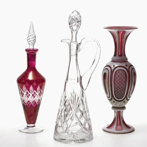 Zwei Karaffen, eine Vase. Farbloses Kristallglas, zwei mit rosalinrotem Überfang. 1 Stöpsel erg., Vase berieben. H. 34-38 cm.